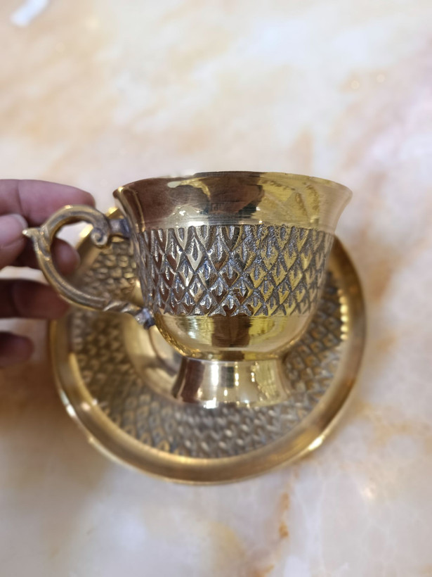 فنجان و نعلبکی برنجی طرح هندی با تزیینات نگیندار و نقشونگار دستی، عرضه شده توسط گالری متالوکس.