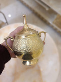 قندان تمام برنجی طلایی دارای درب و دو دسته با حکاکیهای برجسته طرح پرنده و گل روی پسزمینه محو فروشگاه متالوکس