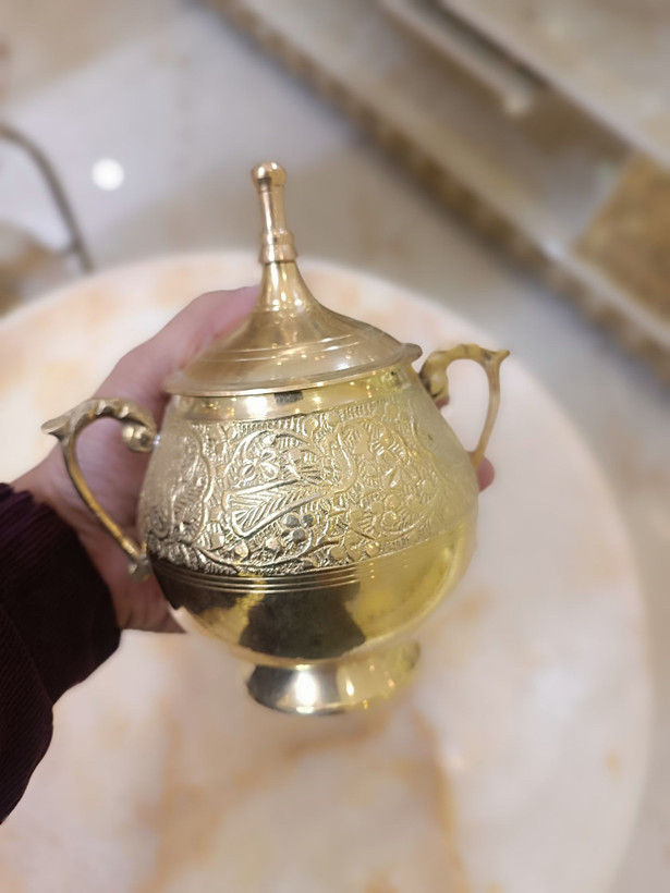 قندان تمام برنجی طلایی دارای درب و دو دسته با حکاکیهای برجسته طرح پرنده و گل روی پسزمینه محو فروشگاه متالوکس