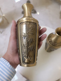 دو عدد گلدان برنجی با رنگ آنتیک و حکاکیهای ظریف طرح گل و گیاه روی میز سفید فروشگاه متالوکس