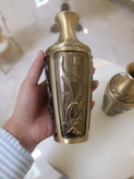 دو عدد گلدان برنجی با رنگ آنتیک و حکاکیهای ظریف طرح گل و گیاه روی میز سفید فروشگاه متالوکس