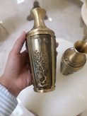 دو عدد گلدان برنجی با رنگ آنتیک و حکاکیهای ظریف طرح گل و گیاه روی میز سفید فروشگاه متالوکس