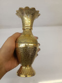 نمای نزدیک از گلدان تک برنجی طلایی با حکاکیهای بسیار پرکار و ظریف و دهانه گلمانند روی پسزمینه روشن متالوکس